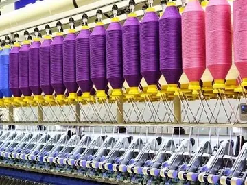 Rows of coloured yarn cones on spinning frames in a textile mill